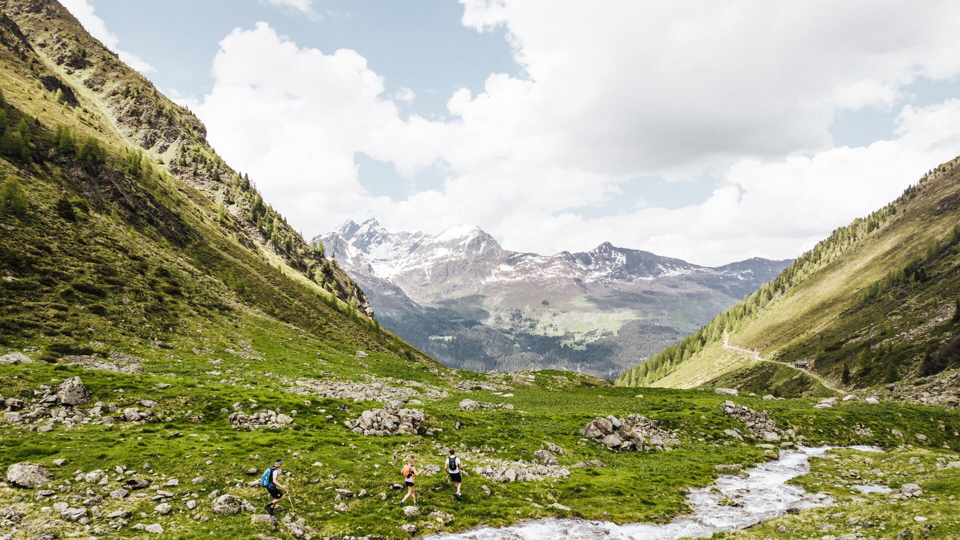 Eine kleine, sommerlich gekleidete Wandergruppe überquert einen eindrucksvollen Abschnitt des Paznauer Höhenweges.