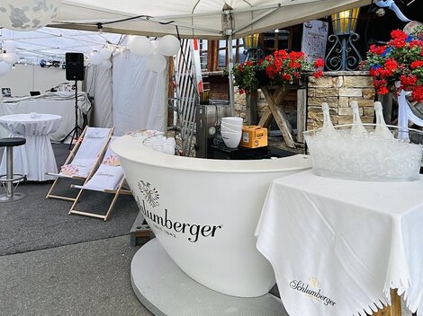 Ein Außenzelt mit einem eleganten Empfangstresen und Blumenarrangements. Der Bereich scheint für eine Veranstaltung oder Feier vorbereitet zu sein.