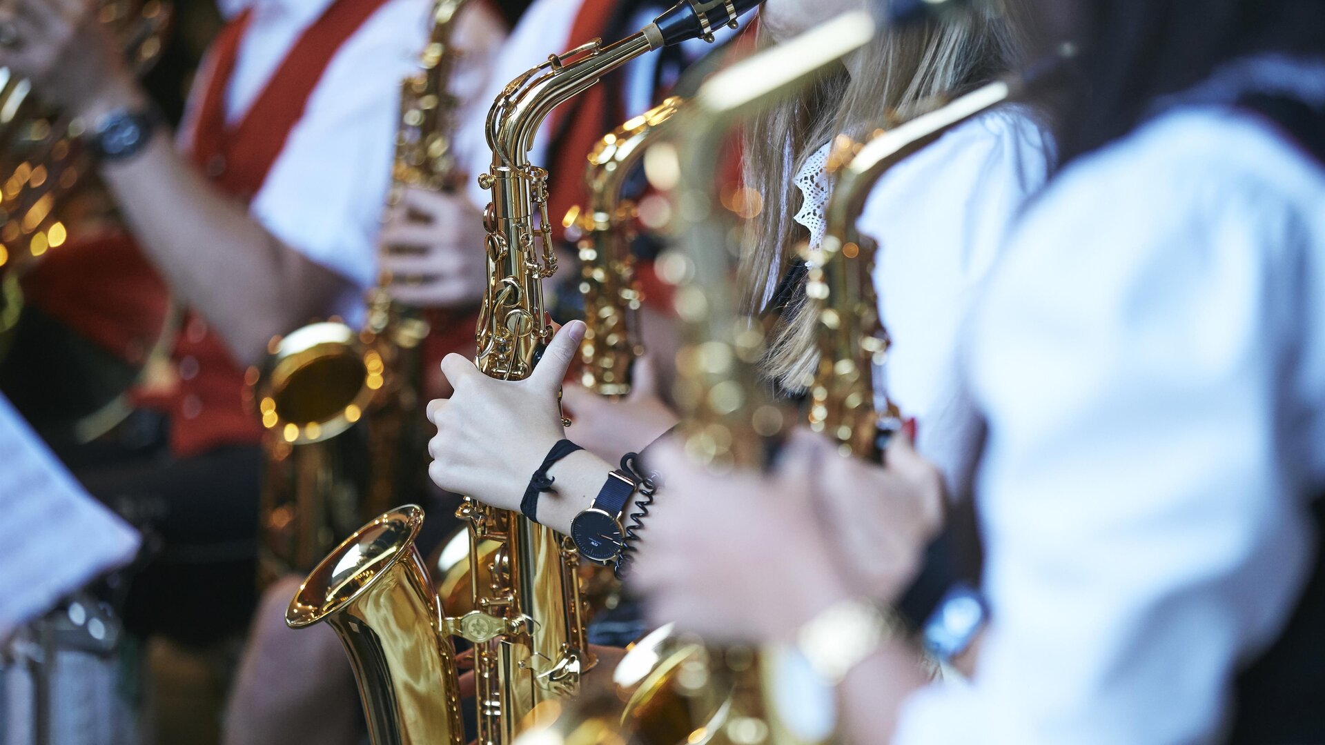 A group of musicians is playing saxophone. They are wearing traditional clothing and focusing on their instruments.