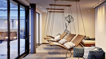 A modern relaxation room with hanging swings and large windows. The cozy atmosphere is accentuated by subtle lighting and stylish furniture.