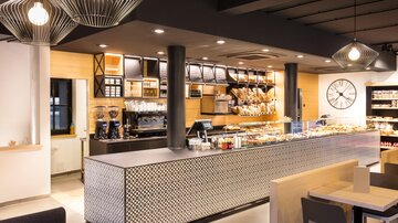 A modern café with an elegant counter and a selection of fresh baked goods. The atmosphere is bright and welcoming.