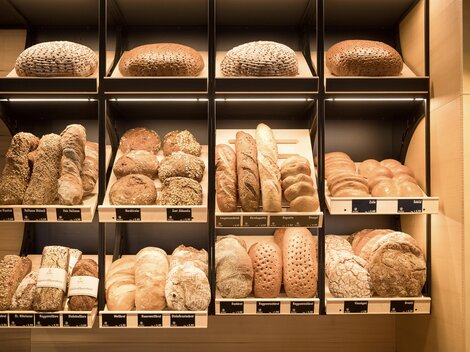 A shelf full of fresh breads in various shapes and sizes. The breads are neatly arranged and offer a selection of different types.