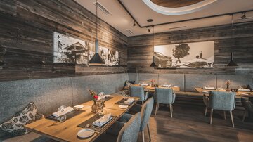 A modern restaurant with wooden walls and elegant tables. The atmosphere is cozy and inviting.