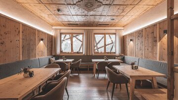 A cozy room with wooden walls and tables made of wood. Large windows provide plenty of daylight and an inviting atmosphere.