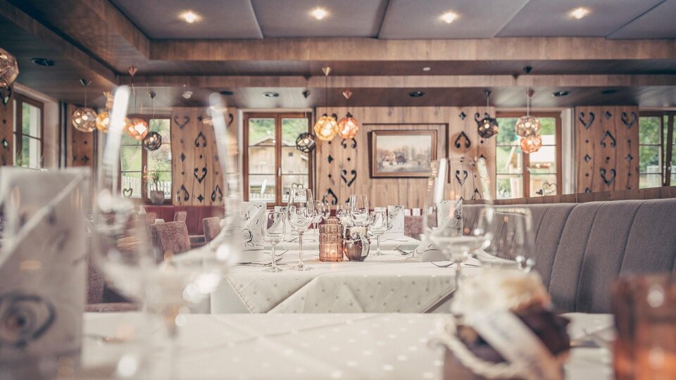 Ein gemütliches Restaurant mit elegant gedeckten Tischen. Weiche Beleuchtung und rustikale Elemente schaffen eine einladende Atmosphäre.