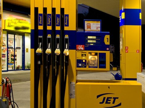 A gas station with several fueling pumps and a cashier area. It is evening, and the surroundings are well-lit.
