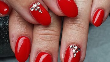 Red fingernails with glossy accents. The nails are oval and well-groomed.