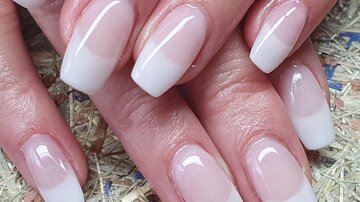 Beautiful, well-groomed fingernails with a white French tip manicure. The nails are long and shiny.