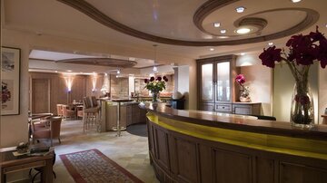 An elegant reception area with wooden decor and gemütlicher lighting. Flower arrangements and an inviting bar create a pleasant atmosphere.